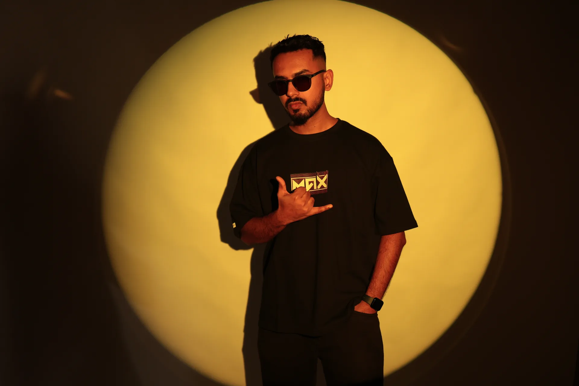 Max in a MAX-branded tee framed by a warm yellow spotlight.
