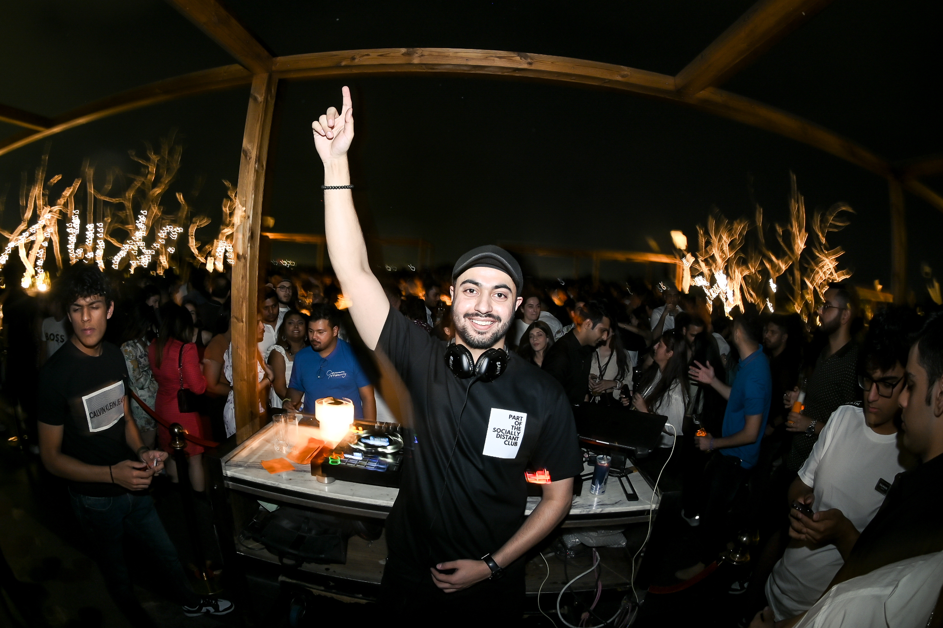 Sahib mid-set at a packed rooftop event, arm raised over the crowd.