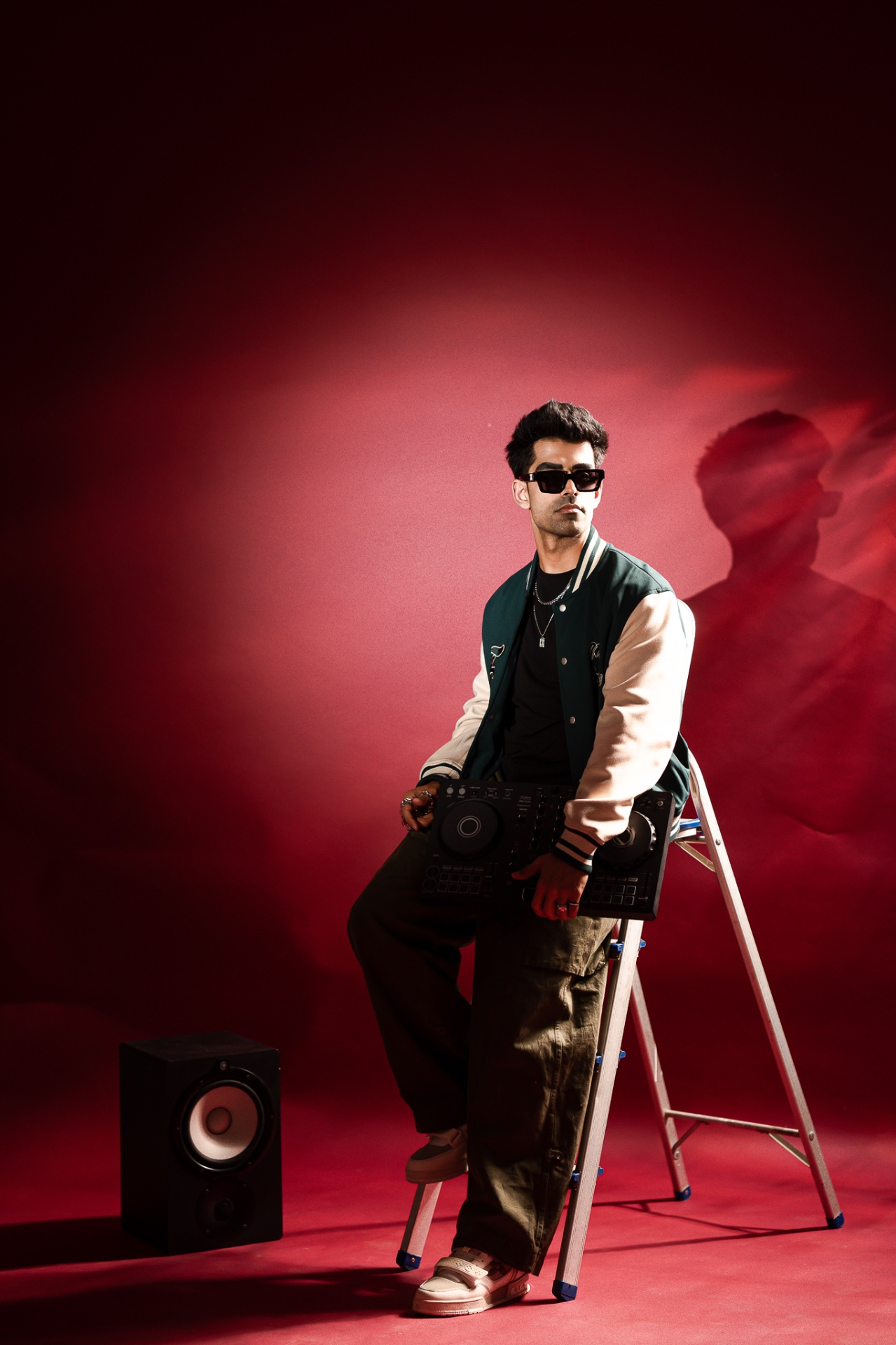 Bahul perched on a ladder with his controller, red-lit studio backdrop.