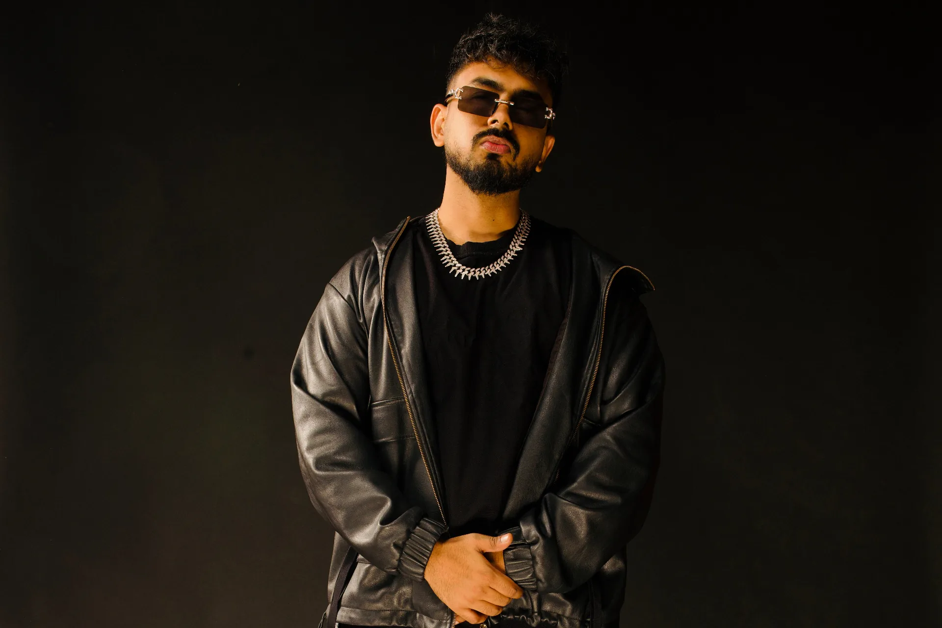 Max in a leather jacket and iced-out chain — editorial studio portrait.
