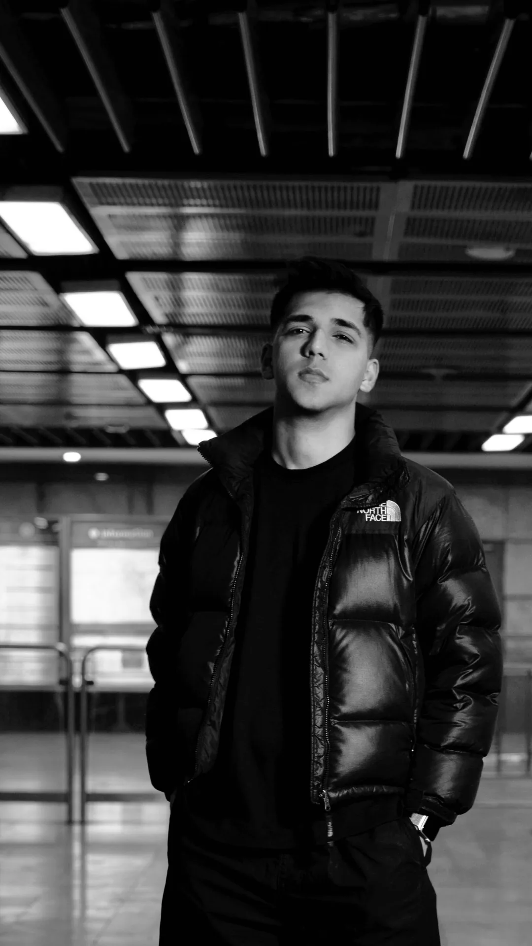Exbow in a North Face puffer, black-and-white station portrait.