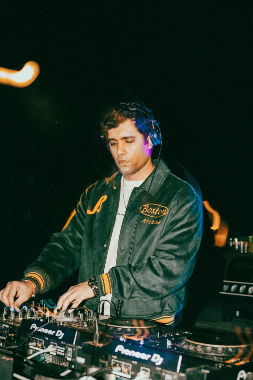 Charit performing live on Pioneer CDJs under club lighting, headphones on mid-mix.